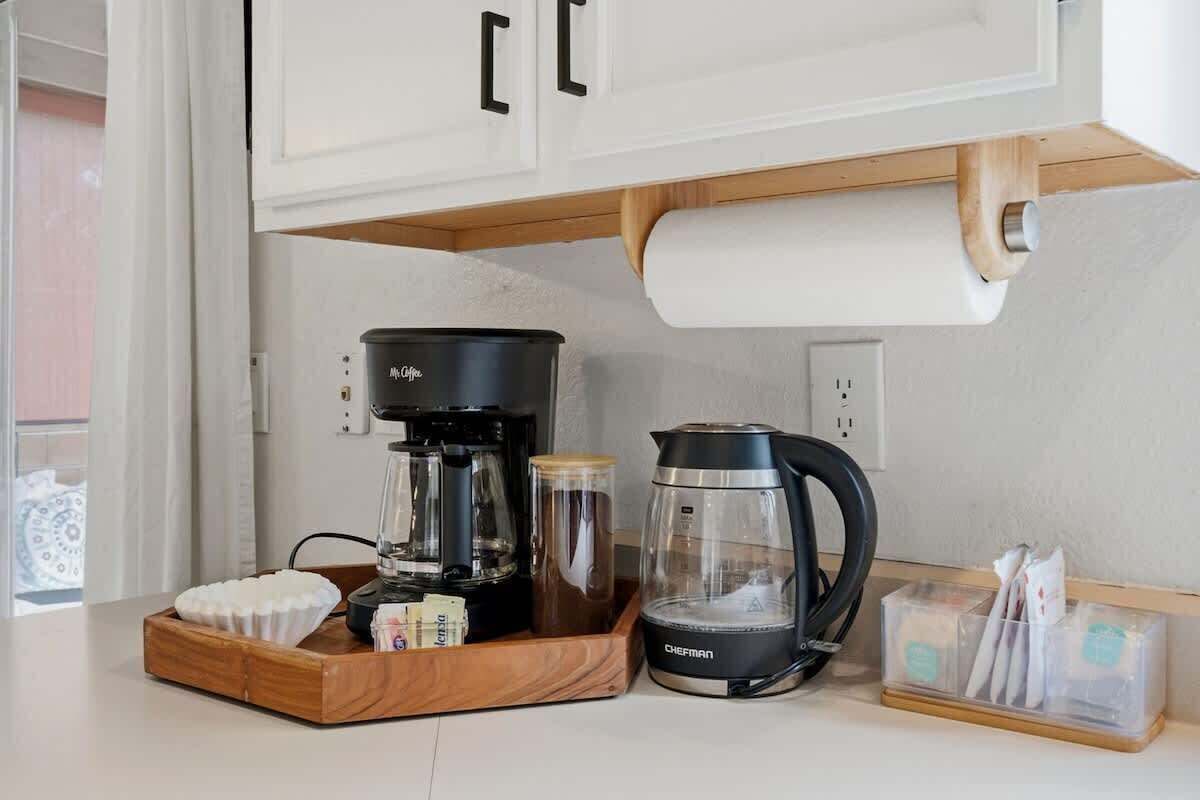 Une cuisine équipée d’une machine à café, d’une bouilloire et d’un plateau contenant des dosettes de café.