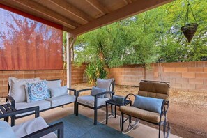 An outdoor patio with a brick wall, a hanging basket, and outdoor furniture including a sofa, chairs, and a table. - Bright & Spacious Family Retreat (Tucson)