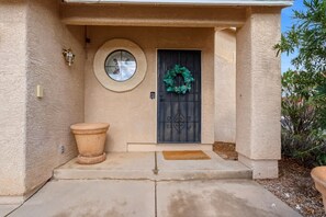 A house entrance with a round window, a door with a wreath, and a small step leading up to the door. - Bright & Spacious Family Retreat (Tucson)
