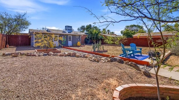 A residential backyard with a patio, a small garden, and a red brick wall. - Bright Desert Retreat Pet Friendly (Tucson)