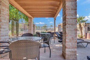 Une terrasse extérieure aménagée avec des meubles en osier, une pergola et une vue sur les environs.