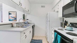 A compact kitchen with white cabinets, a sink, a stove, and a refrigerator. - Cute Townhome with Community Pool 5 mins to TMC (Tucson)
