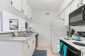 A compact kitchen with white cabinets, a sink, a stove, and a refrigerator. - Cute Townhome with Community Pool 5 mins to TMC (Tucson)