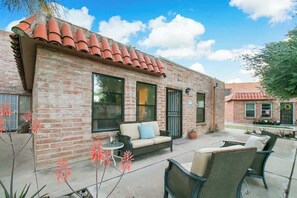 A brick building with a patio area, a sofa, and outdoor chairs. - Cute Townhome with Community Pool 5 mins to TMC (Tucson)