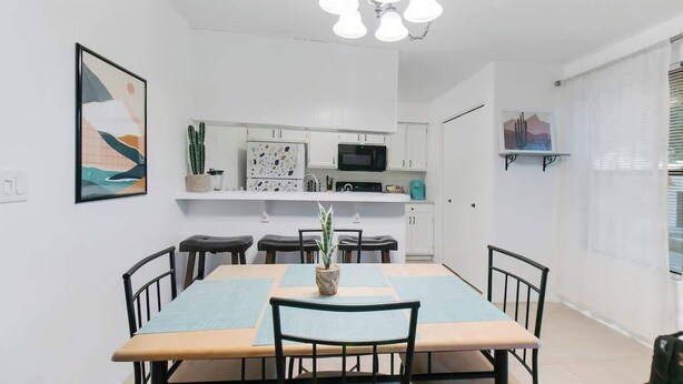 A dining area with a table, chairs, a plant, and a kitchen in the background. - Cute Townhome with Community Pool 5 mins to TMC (Tucson)