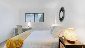 A bedroom with a bed, bedside table, lamp, and a window with blinds. - Cute Townhome with Community Pool 5 mins to TMC (Tucson)