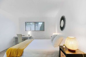 A bedroom with a bed, bedside table, lamp, and a window with blinds. - Cute Townhome with Community Pool 5 mins to TMC (Tucson)