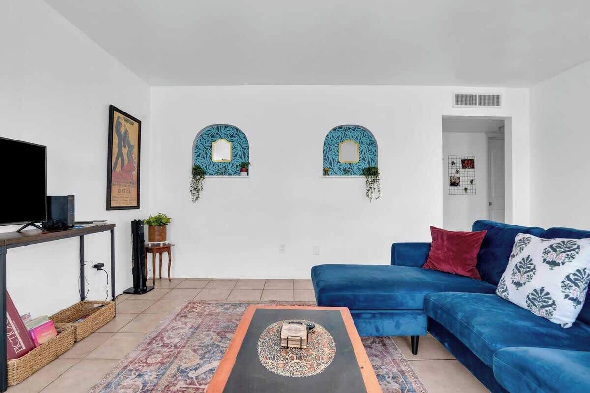 Ein Wohnzimmer mit blauem Sofa, Couchtisch, Fernseher und zwei Wanddekorationen.