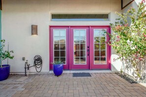 A building with a pink double door, a potted plant, and a hose on the ground. - Pet Friendly-Walk to 4th Ave & Downtown! (Tucson)