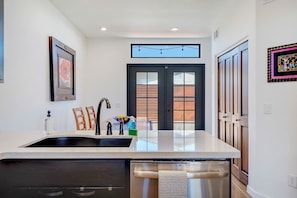 A modern kitchen with a central island, double doors, and a view to the outside. - Pet Friendly-Walk to 4th Ave & Downtown! (Tucson)