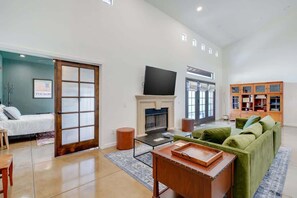 A spacious living room with a fireplace, a green sofa, a flat-screen TV, and a wooden coffee table. - Pet Friendly-Walk to 4th Ave & Downtown! (Tucson)