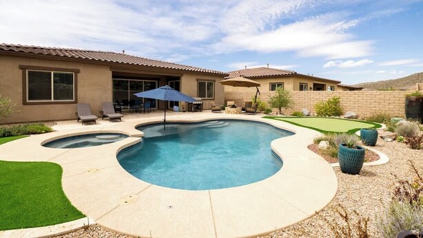 A residential backyard with a swimming pool, patio furniture, and a small putting green. - Gated Desert Oasis w/ Pool (Marana)