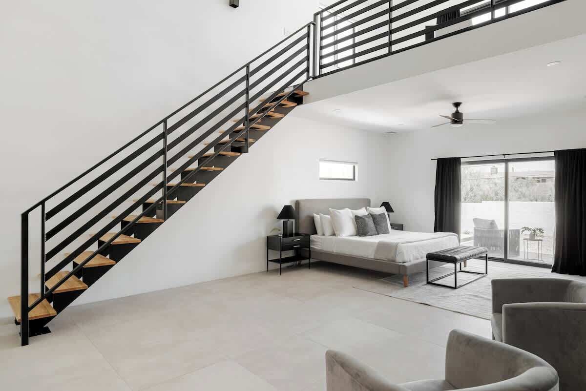Ein modernes Wohnzimmer mit Treppe, einem Bett, einer Couch und einem Essbereich.
