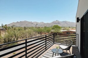A balcony with a view of mountains, a chair, and a small table. - Foothills Upscale Retreat with Heated Pool (Tucson)