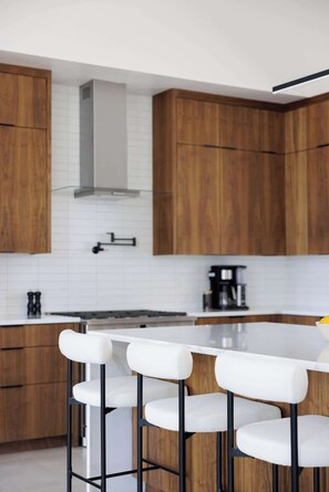 A modern kitchen with wooden cabinets, a white countertop, and a bar stool area. - Foothills Upscale Retreat with Heated Pool (Tucson)