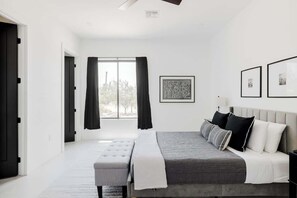Een slaapkamer met een bed, een bankje en kunst aan de muur.
