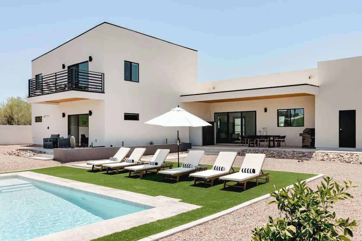 A modern two-story house with a swimming pool, outdoor seating, and a patio area.