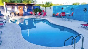 A swimming pool with red chairs and a small building with a door and windows. - Warm & Quaint Retreat with Pool (Tucson)