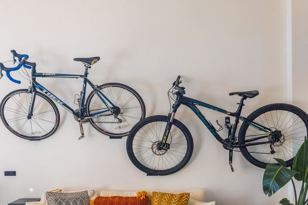 Zwei an der Wand montierte Fahrräder, ein Sofa mit gemusterten Kissen und eine Pflanze.