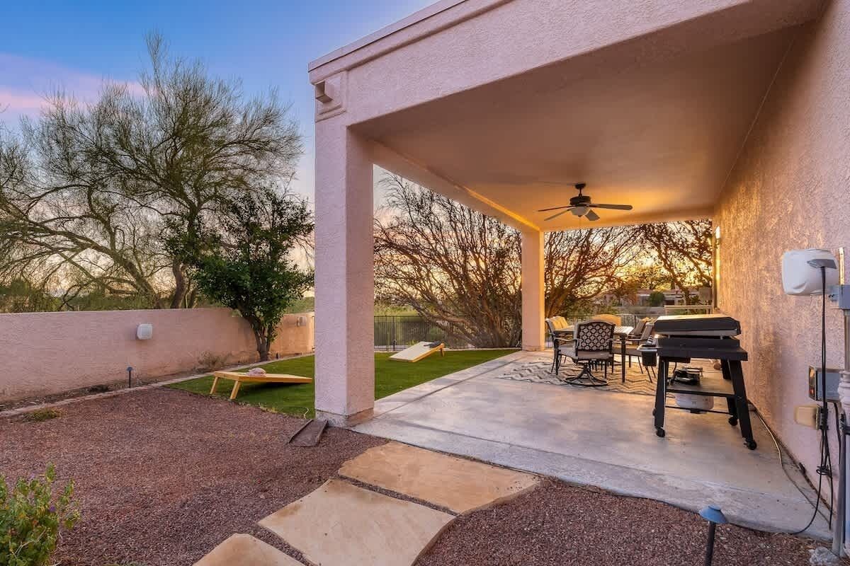 A covered patio area with a ceiling fan, outdoor furniture, and a grill.