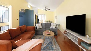 Ein Wohnzimmer mit einer Couch, einem Couchtisch, einem Flachbildfernseher und einem Deckenventilator.