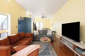 Ein Wohnzimmer mit einer Couch, einem Couchtisch, einem Flachbildfernseher und einem Deckenventilator.