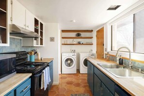 A compact kitchen with a stove, oven, washing machines, and a sink. - Midtown Retreat-Pet Friendly (Tucson)