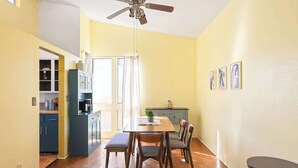 Ein Essbereich mit Tisch, Stühlen, Deckenventilator und einer Küche im Hintergrund.