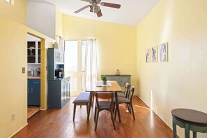 Ein Essbereich mit Tisch, Stühlen, Deckenventilator und einer Küche im Hintergrund.