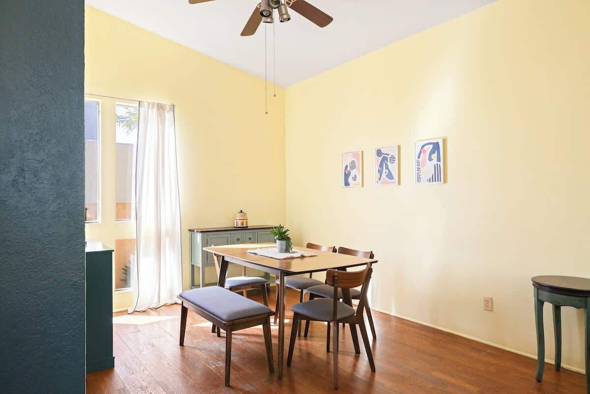 A dining area with a table and chairs, a ceiling fan, and a window with curtains.