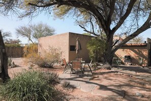 A desert-style building with a patio area, outdoor furniture, and a large tree. - Midtown Retreat-Pet Friendly (Tucson)