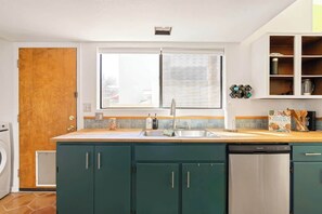 A kitchen with a dishwasher, a sink, and a window. - Midtown Retreat-Pet Friendly (Tucson)