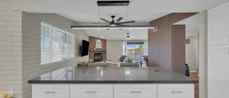 A modern kitchen with a large island, white cabinetry, and a ceiling fan.