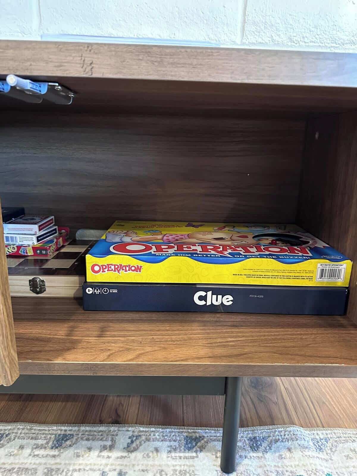 A wooden shelf with a box of Operation game and a Clue game.