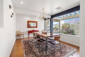 A dining area with a wooden table, chairs, a chandelier, and a view of the outdoors. - Cactus & Sky Escape with POOL and SPA! (Tucson)