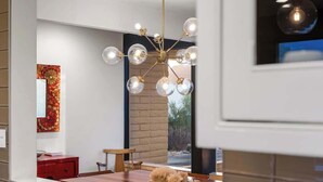 A modern kitchen with a central island, a chandelier, and a red cabinet. - Cactus & Sky Escape with POOL and SPA! (Tucson)