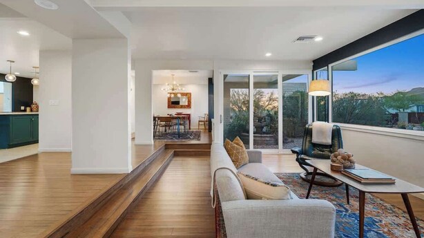 A modern interior with a sofa, dining area, and a view through large windows. - Cactus & Sky Escape with POOL and SPA! (Tucson)