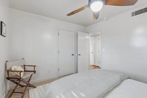 Ein Schlafzimmer mit einem Bett, einem Deckenventilator und einem Sessel.