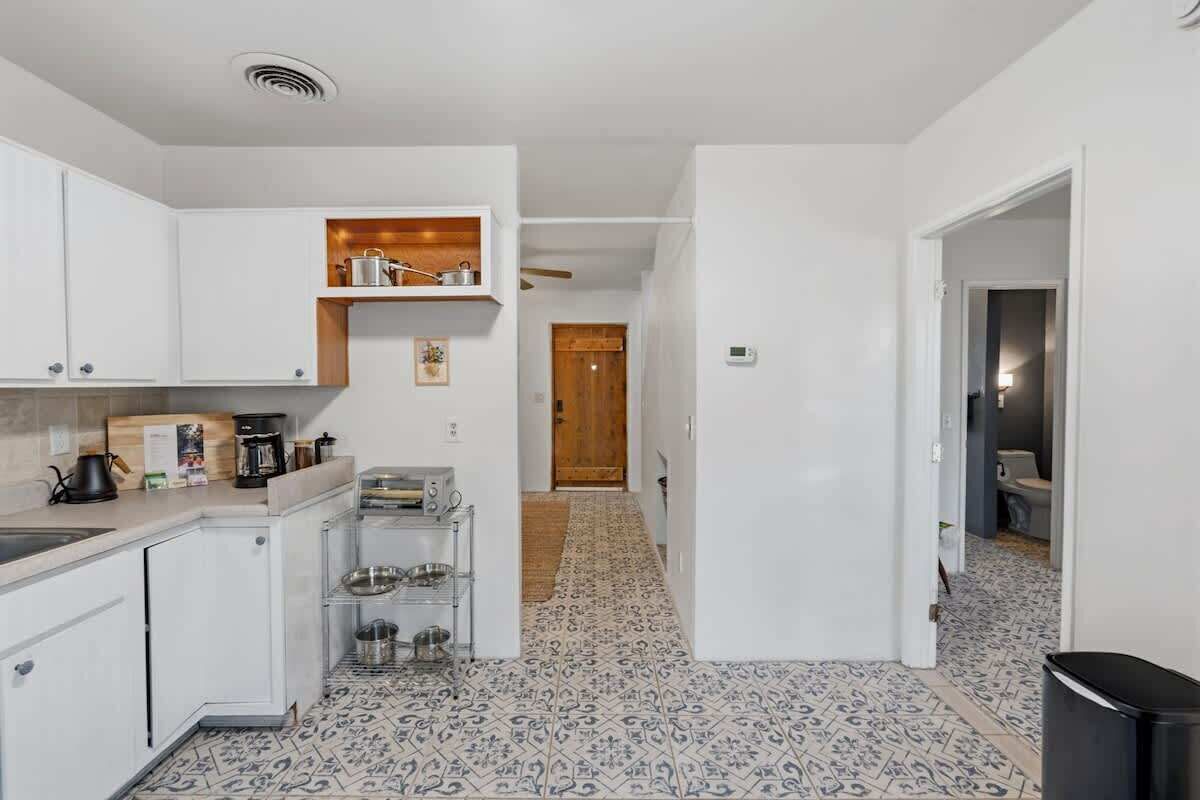 A compact kitchen with white cabinets, a coffee machine, and a patterned floor.