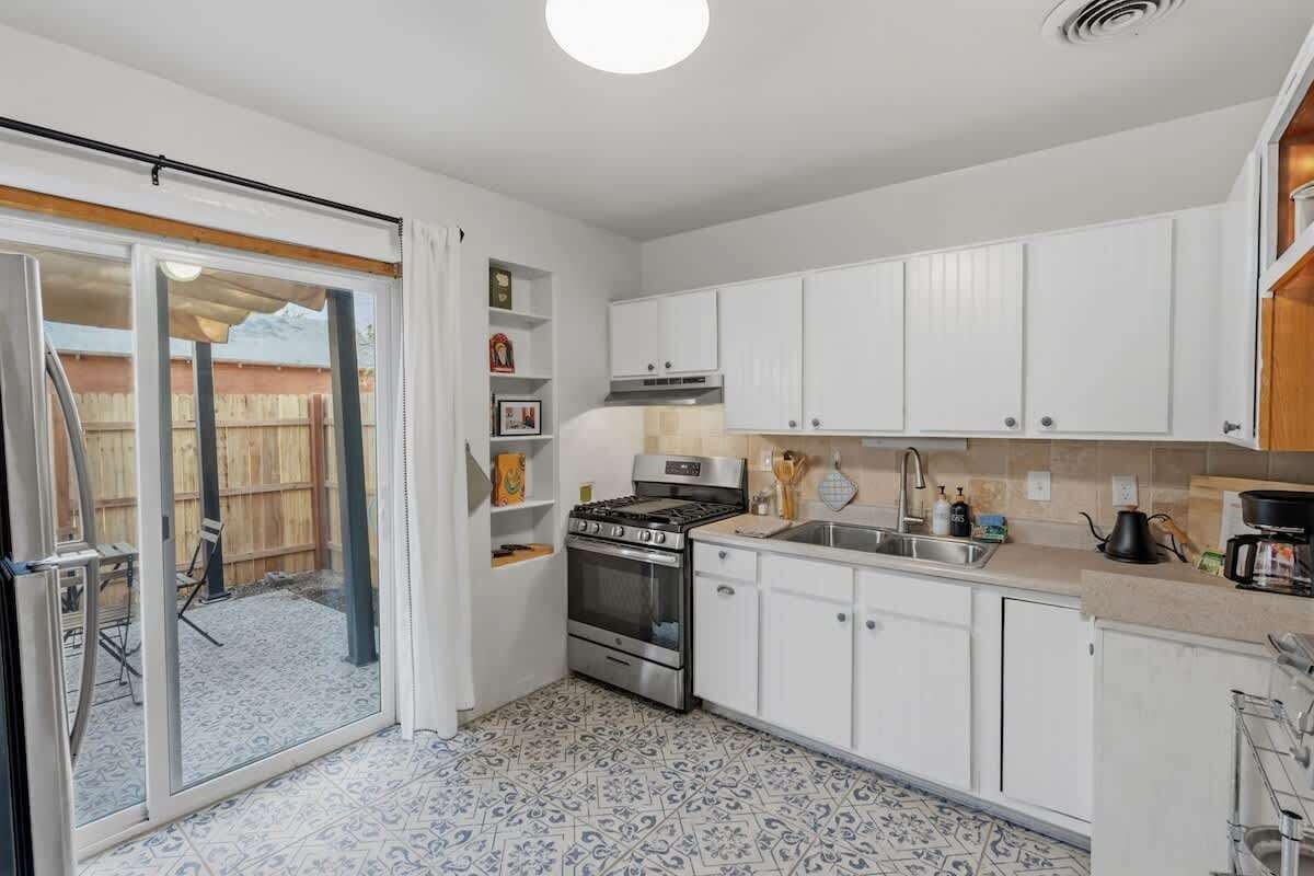 A compact kitchen with white cabinets, a gas stove, an oven, a sink, and a small dining area with a table and chairs.