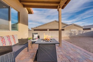 An outdoor patio with a fire feature, seating, and a view of a building in the background. - Desert Escape- 5 Mins to Starr Pass & Hiking (Tucson)
