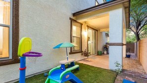 Ein Garten mit Spielbereich, Picknicktisch und überdachter Sitzgelegenheit.
