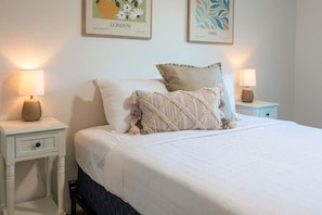A neatly made bed with a white duvet, two pillows, and a bedside table with a lamp. - Peaceful 2 Story Home-Pet Friendly (Tucson)