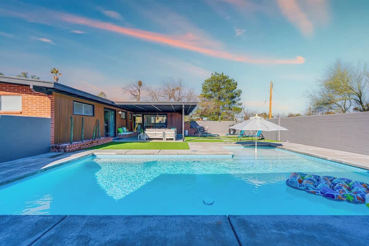 Une maison moderne dotée d’une piscine, d’un patio couvert et d’un jardin aménagé.