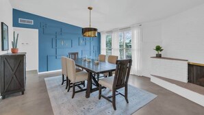 A dining area with a blue accent wall, a wooden table, and chairs. - Mid-Century Desert Galore/Mt.Views/Pool (Tucson)