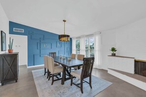 A dining area with a blue accent wall, a wooden table, and chairs. - Mid-Century Desert Galore/Mt.Views/Pool (Tucson)