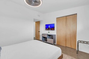 A bedroom with a bed, a TV, a wooden wardrobe, and a small desk with drawers. - Mid-Century Desert Galore/Mt.Views/Pool (Tucson)