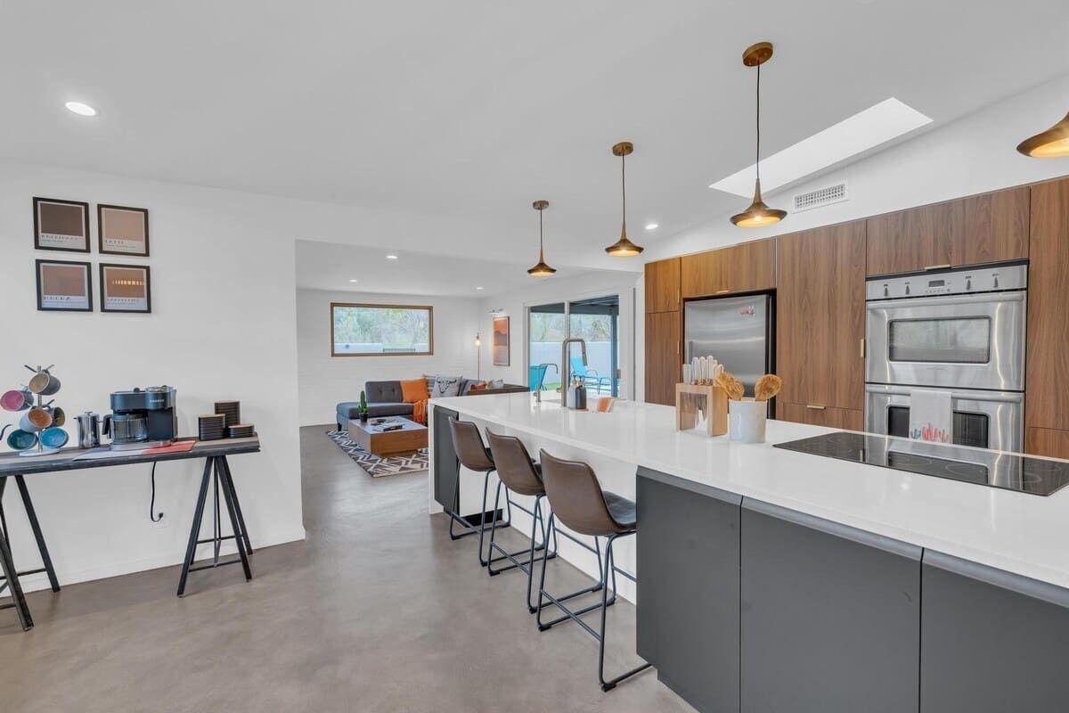 Une cuisine moderne dotée d’un grand îlot central, d’appareils électroménagers en acier inoxydable et d’un coin bar.