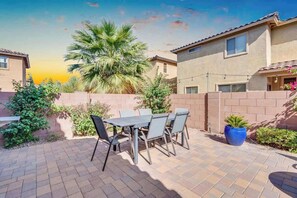 Eine Terrasse mit Tisch und Stühlen, eine Palme und ein Gebäude im Hintergrund.