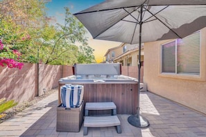 A hot tub with a canopy, a lounge chair, and a small table with a striped towel. - Family Home-mins from the LOOP with Hot Tub! (Tucson)